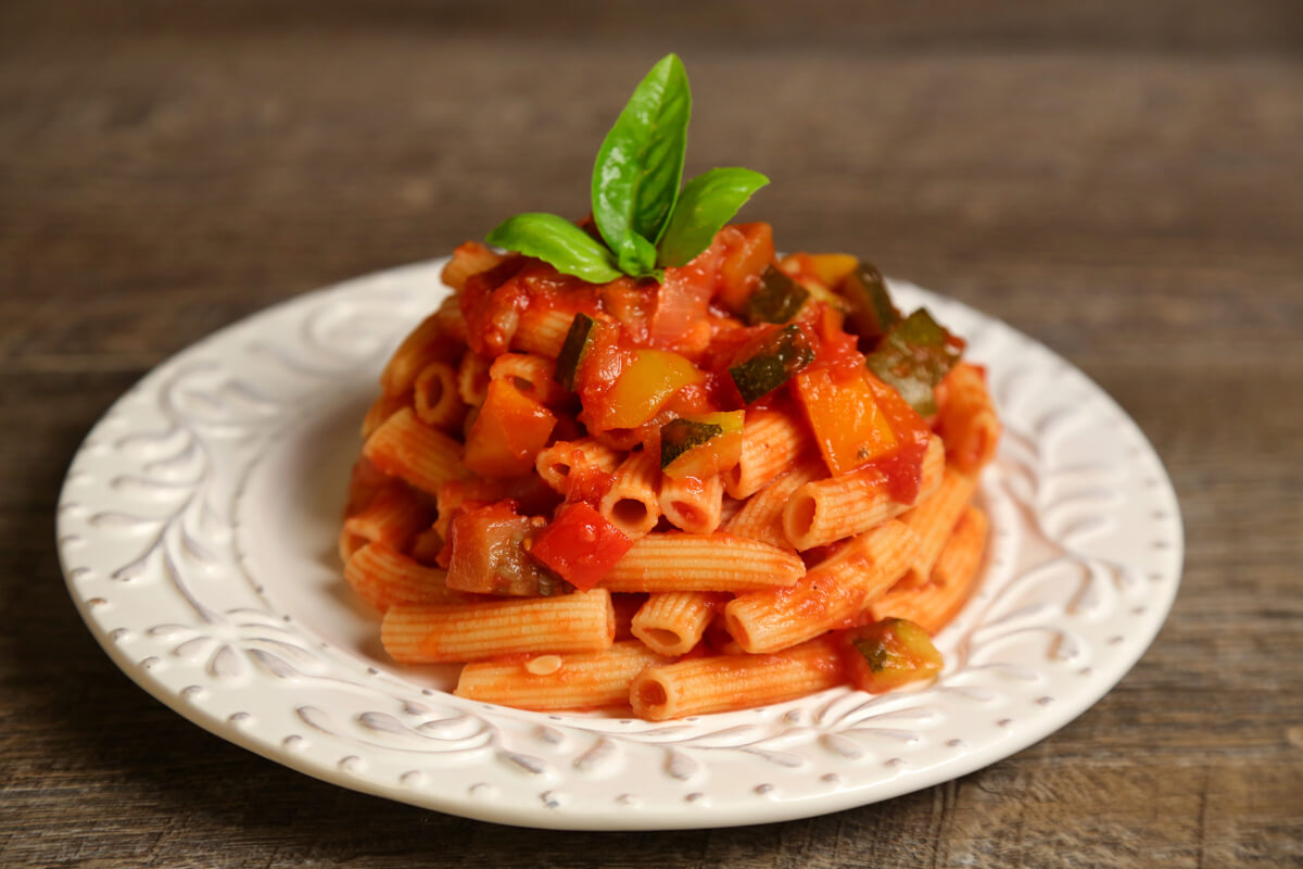 Rigatoni pasta is tubular in shape and loved for its ability to hold sauces and grated cheese on its ridges. It resembles penne but with square-cut ends and often slightly curved. Rigatoni is the favorite pasta shape in the south of Italy and Sicily. It is perfect with any sauce, from cream to the chunkiest meat sauces.